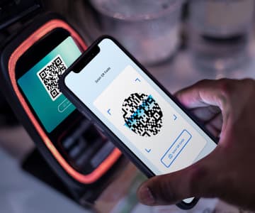 Person holding a smartphone displaying a QR code for cashless payment